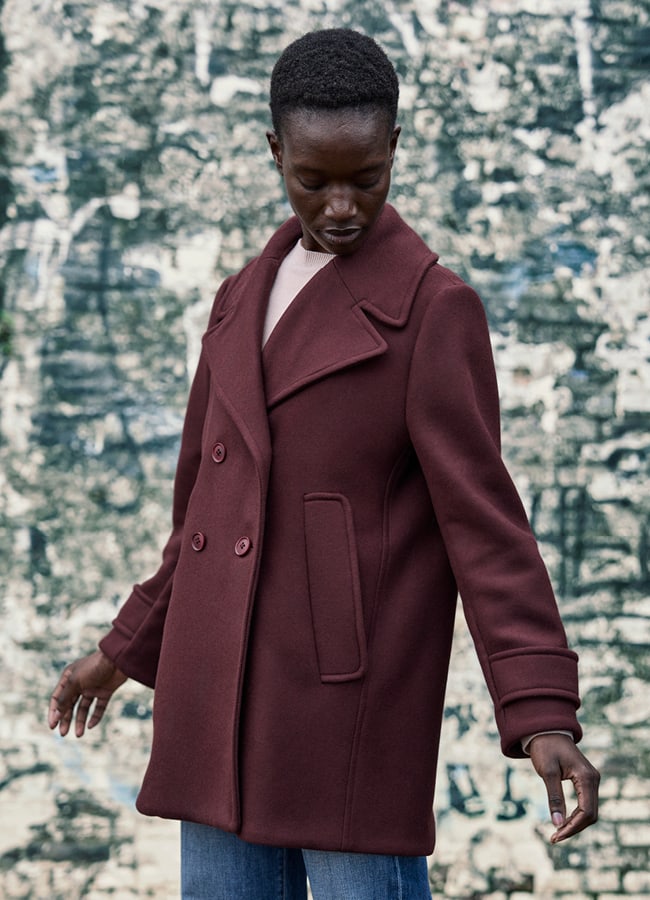 Frau mit Jacke Jil Bordeaux vor Steinmauer