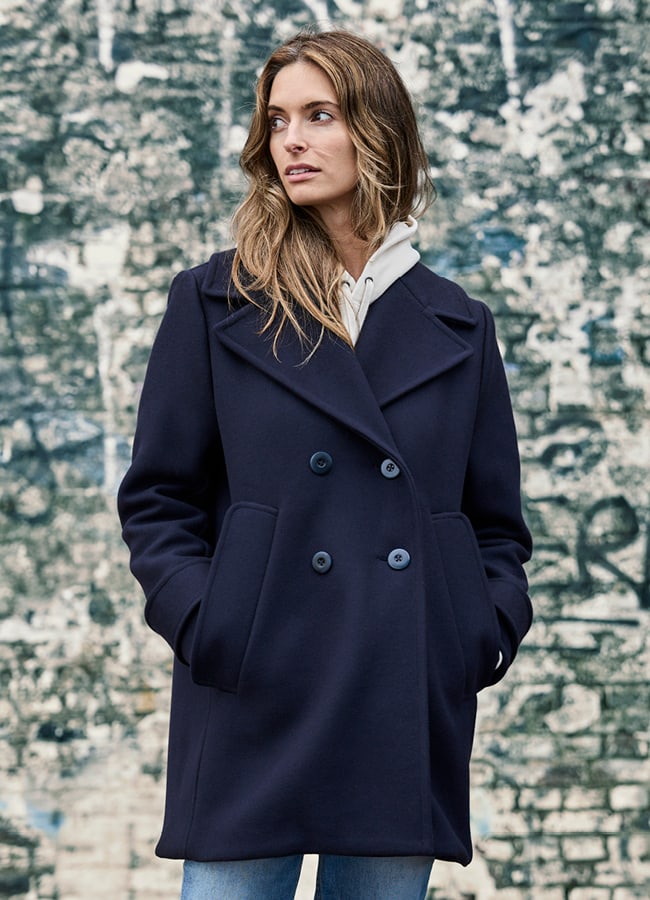 Frau mit Jacke Jil Navy vor Steinmauer